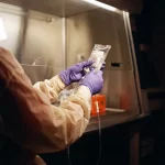 Imagem ilustrativa: Enfermeira prepara bolsa de infusão em cabine de segurança biológica