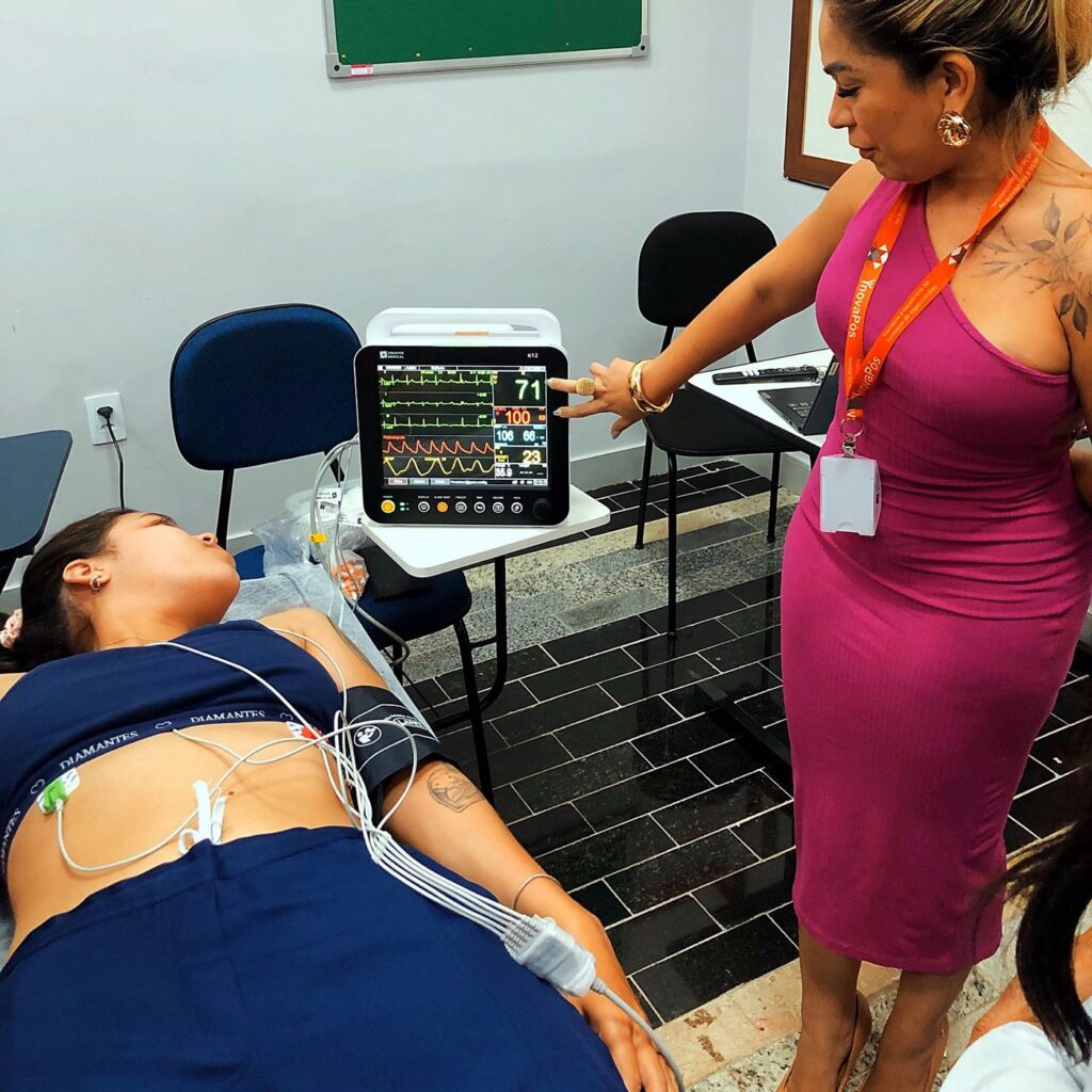 Professora lê o monitor multiparâmetro com a turma na pós em Urgência e Emergência e UTI